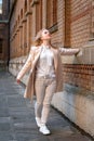 Young woman in white clothes near old red brick building looking up. Girl walks alone. Vertical frame Royalty Free Stock Photo