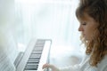 Young woman in white clothes sitting and playing an electronic piano Royalty Free Stock Photo