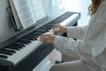 Young woman in white clothes sitting and playing an electronic piano Royalty Free Stock Photo