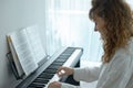 Young woman in white clothes sitting and playing an electronic piano Royalty Free Stock Photo