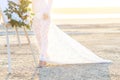 Young woman in white dress on the beach. It stands next to an easel decorated with flowers. On the Sunset