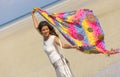 Young woman with white dress dancing on the beach with a colorful sarong Royalty Free Stock Photo