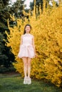 Young woman has a fun and jumps near blooming forsythia bushes