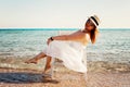 Young woman in white dress and hat sitting in a chair in the sea Royalty Free Stock Photo