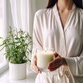 Young woman holding burning candle jar in her hands, container candle mockup closeup shot, mindfulness home interior Royalty Free Stock Photo