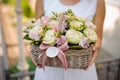 Woman holds a wicker basket full of roses and ranunkulus Royalty Free Stock Photo