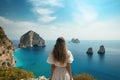 Young woman in white dress looking at the sea and cliffs on the island of Zakynthos, Greece, Holidays on Capri Island. Back view