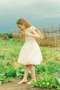 Beautiful young woman in white dress relaxing in apple tree garden. Girl with bare feet in summer