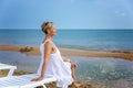 A young woman in a white dress sits on a sandy beach. Tourism, travel and freedom Royalty Free Stock Photo