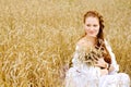 Young woman in white dress sitting in field with wheat Royalty Free Stock Photo