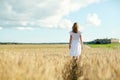Young woman in white dress walking along on field Royalty Free Stock Photo