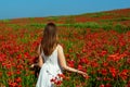 Young woman in a white dress walks on a poppy field. Royalty Free Stock Photo