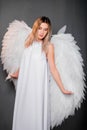 woman in a white dress with white wings behind her back. Girl in the image of an angel isolated on a gray background Royalty Free Stock Photo