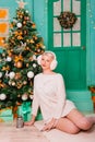 Young woman in white, fluffy headphones in Christmas decorations. a carpet in the New Year against the backdrop of a large