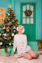 Young woman in white, fluffy headphones in Christmas decorations. a carpet in the New Year against the backdrop of a large