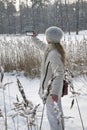 Young woman in a white jacket photographs a panorama of the coast of the winter forest lake on the phone Royalty Free Stock Photo