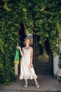 Young woman in a white long dress holding a green mesh bag in her hands Royalty Free Stock Photo