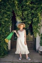 Young woman in a white long dress holding a green mesh bag in her hands Royalty Free Stock Photo