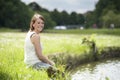 Young woman in white seated at the lake