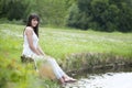 Young woman in white seated at the lake