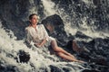 Young woman in white shirt and bikini lies on rock in water flow Royalty Free Stock Photo