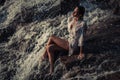 Young woman in white shirt and bikini sits on rock in water flow Royalty Free Stock Photo