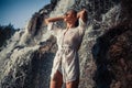 Young woman in white shirt and bikini stands near waterfall. Royalty Free Stock Photo