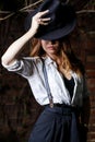 Young woman in white shirt and black hat standing in the darkness. Royalty Free Stock Photo