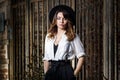 Young woman in white shirt and black hat standing near the gate. Royalty Free Stock Photo