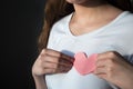 Young woman in white shirt holding pink paper heart against chest Royalty Free Stock Photo