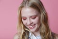 Young woman in white shirt is smiling look down, pink background Royalty Free Stock Photo