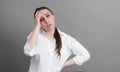 Young woman in a white shirt tired, pensive on a gray