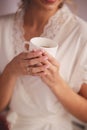 Young woman in white silk robe with white cup of beverage tea or coffee in the morning Royalty Free Stock Photo