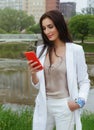 Young woman in a white suit and smartphone in hand in the park in summer Royalty Free Stock Photo