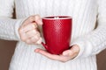 Young woman in white sweater is holding red cup of tea or coffee Royalty Free Stock Photo