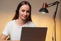 Young woman in a white T-shirt and headset is working on a laptop computer at home. Work at home, Video conference Royalty Free Stock Photo