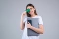 Young woman in white t-shirt holding credit card near face and laptop, isolated over gray background. Pay wit credit or Royalty Free Stock Photo