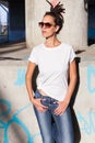 Young woman in white t shirt and jeans with dreadlocks hairstyle sunglasses and outdoor in city spring summer day
