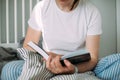 Young woman reading book on bed at home. Concept of cozy, comfort home. Lifestyle, slow living Royalty Free Stock Photo