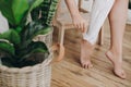 Young woman in white towel applying shaving cream on her legs in home bathroom with green plants. Skin care and wellness concept. Royalty Free Stock Photo