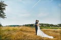 Young woman in a white wedding dress and brutal handsome man in a blue business suit posing outdoors. Loving couple gets