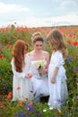 young woman with wild flowers and cute girls in the blooming spring poppy. Mothers day. Royalty Free Stock Photo