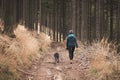 Young woman in winter clothes and her dog Barbu tcheque walks through woods in the early hours. Trust between dog and man.