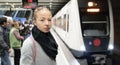 Young woman in winter coat going to work, waiting on the platform of a railway station for train to arrive. Public Royalty Free Stock Photo