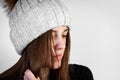Young woman in winter hat with dirty greasy hair on gray background. Royalty Free Stock Photo