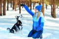 Young woman in winter snowy forest walking with her dog in a winter day. Friendship pet and human. Royalty Free Stock Photo