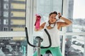 A young woman wipes her face with a towel, exhausted from a heavy cardio workout. Time to rest after the exercise bike Royalty Free Stock Photo