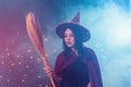 Young woman in witch halloween costume wear witches hat holding broom over spooky dark magic background Royalty Free Stock Photo