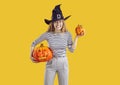 Young woman in witch hat holding Halloween pumpkins and making funny, scary face Royalty Free Stock Photo