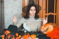 Young woman in witch hat prepares for halloween and keeps fake spiderweb